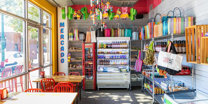 Colorful shelves full of goods at Taco Naco KC with sign that reads